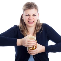 A young woman struggling to open a jar